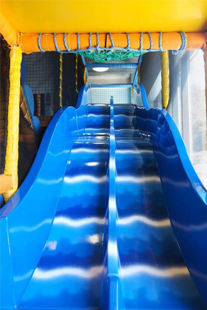 Inside Xcel Leisure Centre Creche play area colourful soft play flooring and a long wavy blue slide.